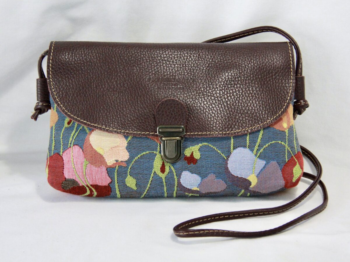 Sac en cuir avec motif de coquelicots en tissu jacquard, artisanal, sur fond bleu. Accessoire floral et élégant.