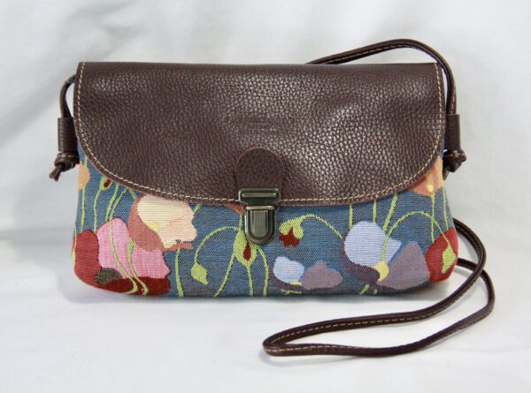 Sac en cuir avec motif de coquelicots en tissu jacquard, artisanal, sur fond bleu. Accessoire floral et élégant.