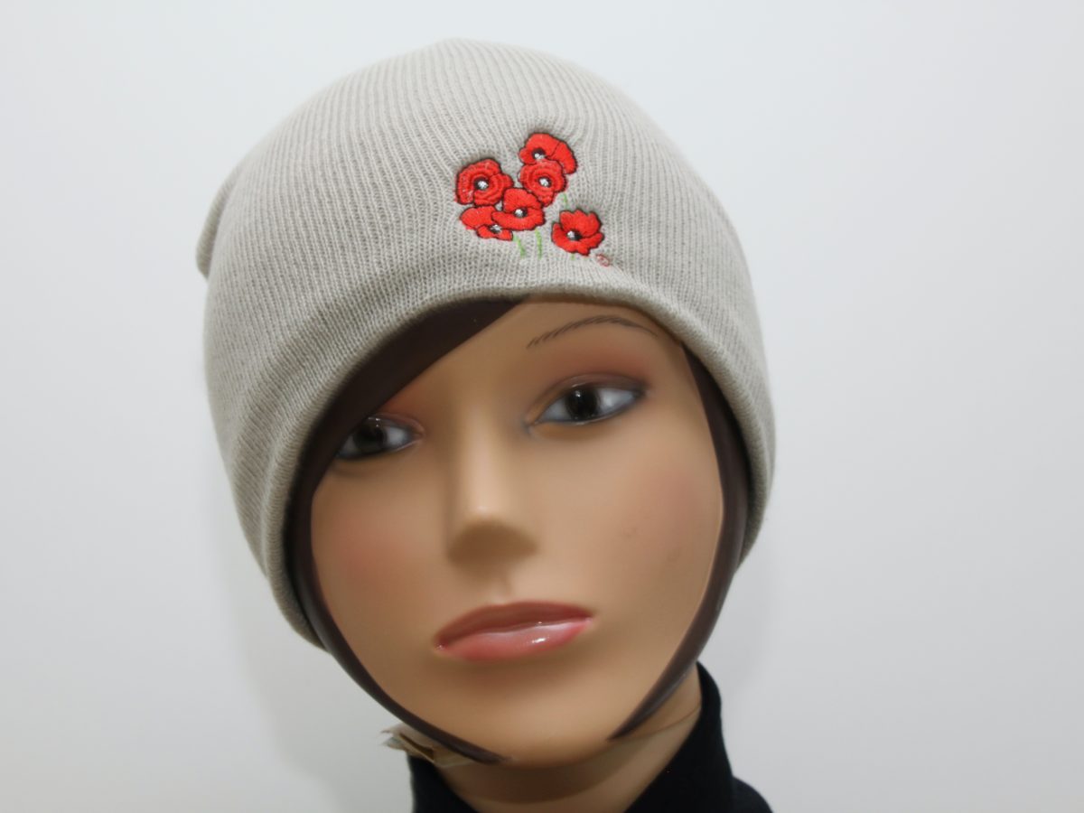 Bonnet beige avec broderie de coquelicots, présenté sur un mannequin. Création artisanale inspirée de l'univers floral.