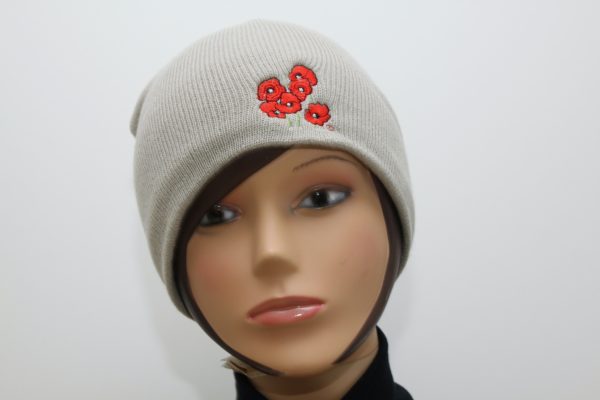 Bonnet beige avec broderie de coquelicots, présenté sur un mannequin. Création artisanale inspirée de l'univers floral.