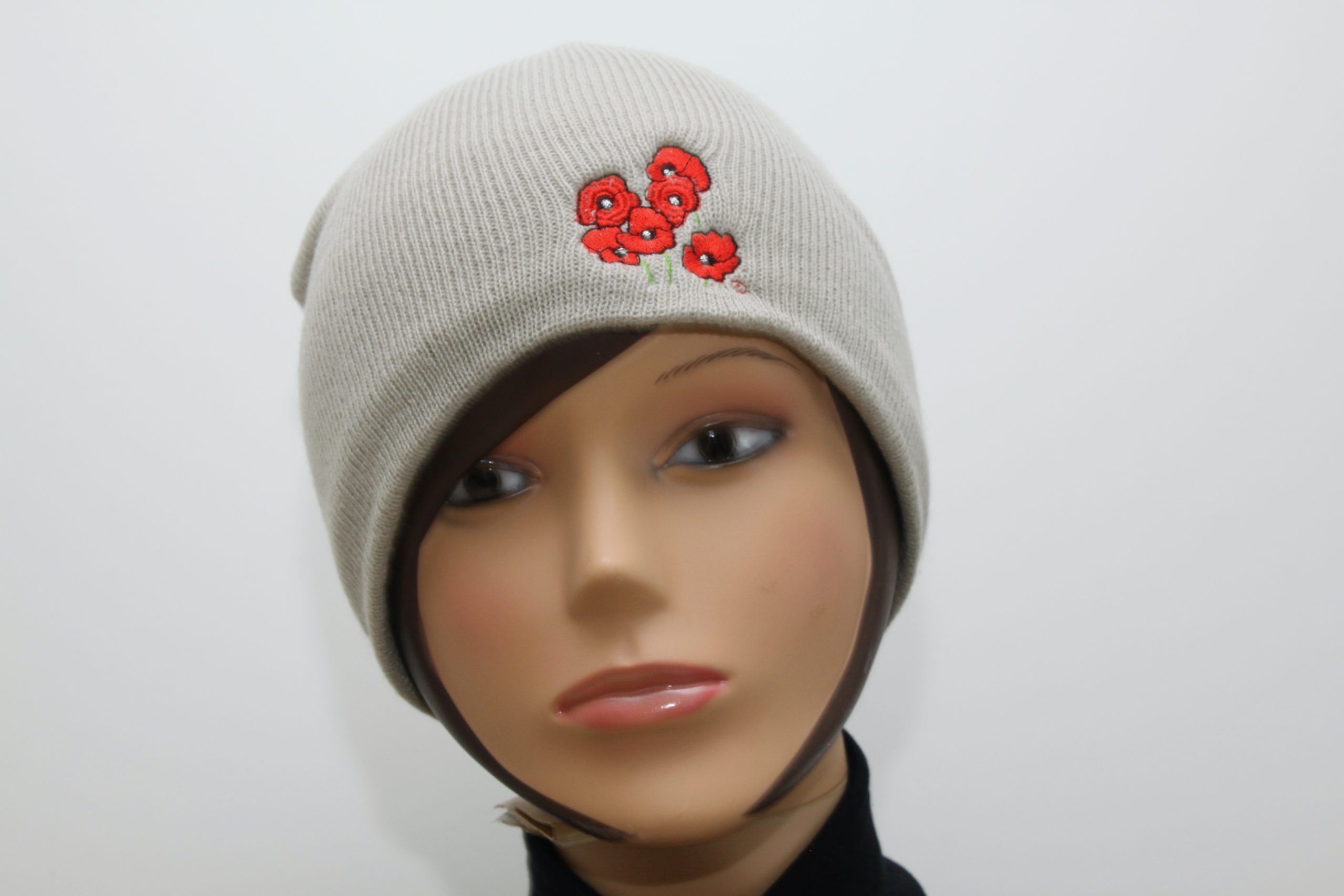 Bonnet beige avec broderie de coquelicots, présenté sur un mannequin. Création artisanale inspirée de l'univers floral.