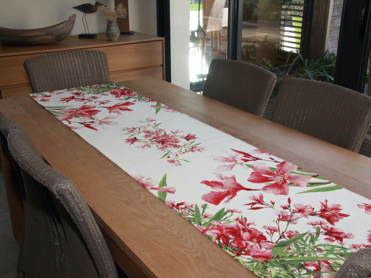 Chemin de table fleuri aux motifs rouges, disposé sur une table en bois.