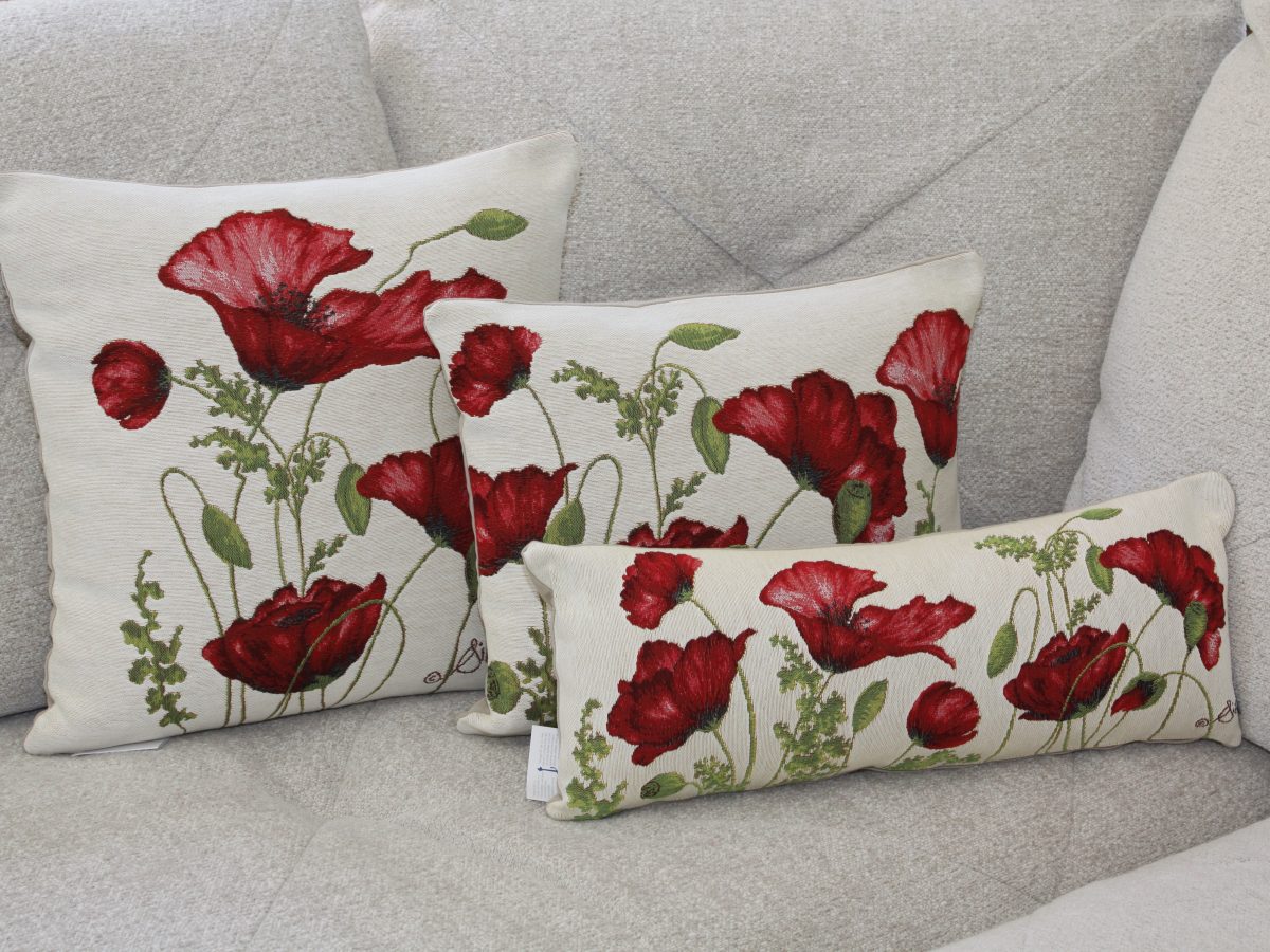 Coussins décoratifs ornés de coquelicots rouges, présentés sur un canapé beige. Créations de Poppies Shop à Bayeux.