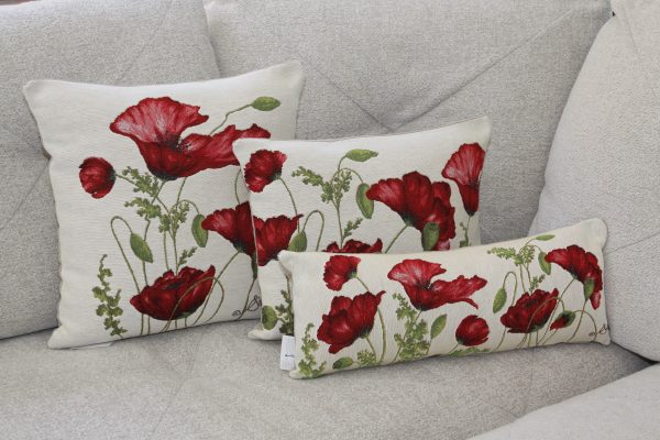 Coussins décoratifs ornés de coquelicots rouges, présentés sur un canapé beige. Créations de Poppies Shop à Bayeux.