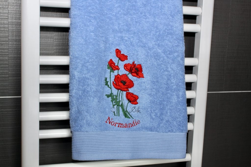 Blue bath towel with poppy embroidery and the inscription "Normandie".