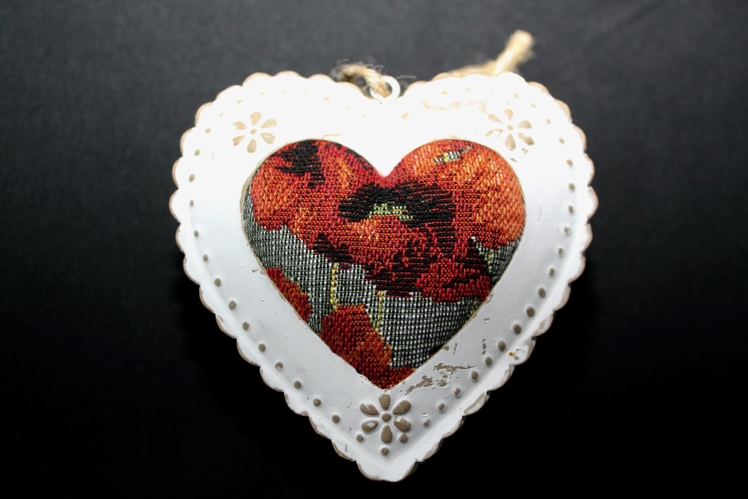 Cœur en métal décoré d'un motif floral, au centre un tissu jacquard représentant des coquelicots, suspendu par une corde.