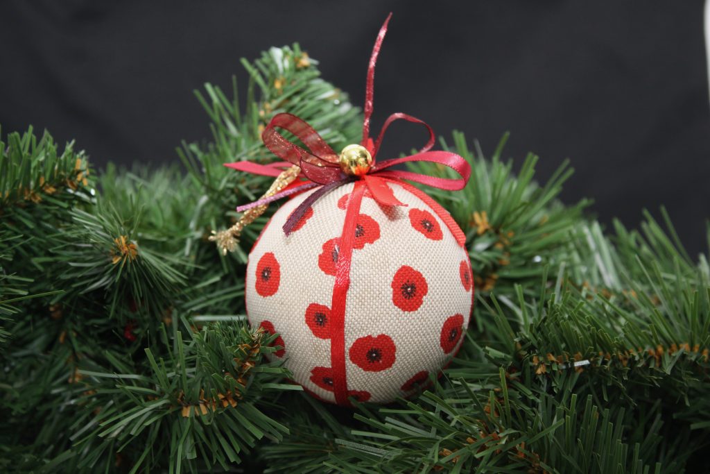 Boule de Noël en tissu crème ornée de coquelicots rouges, avec un ruban. Décoration originale pour les fêtes.
