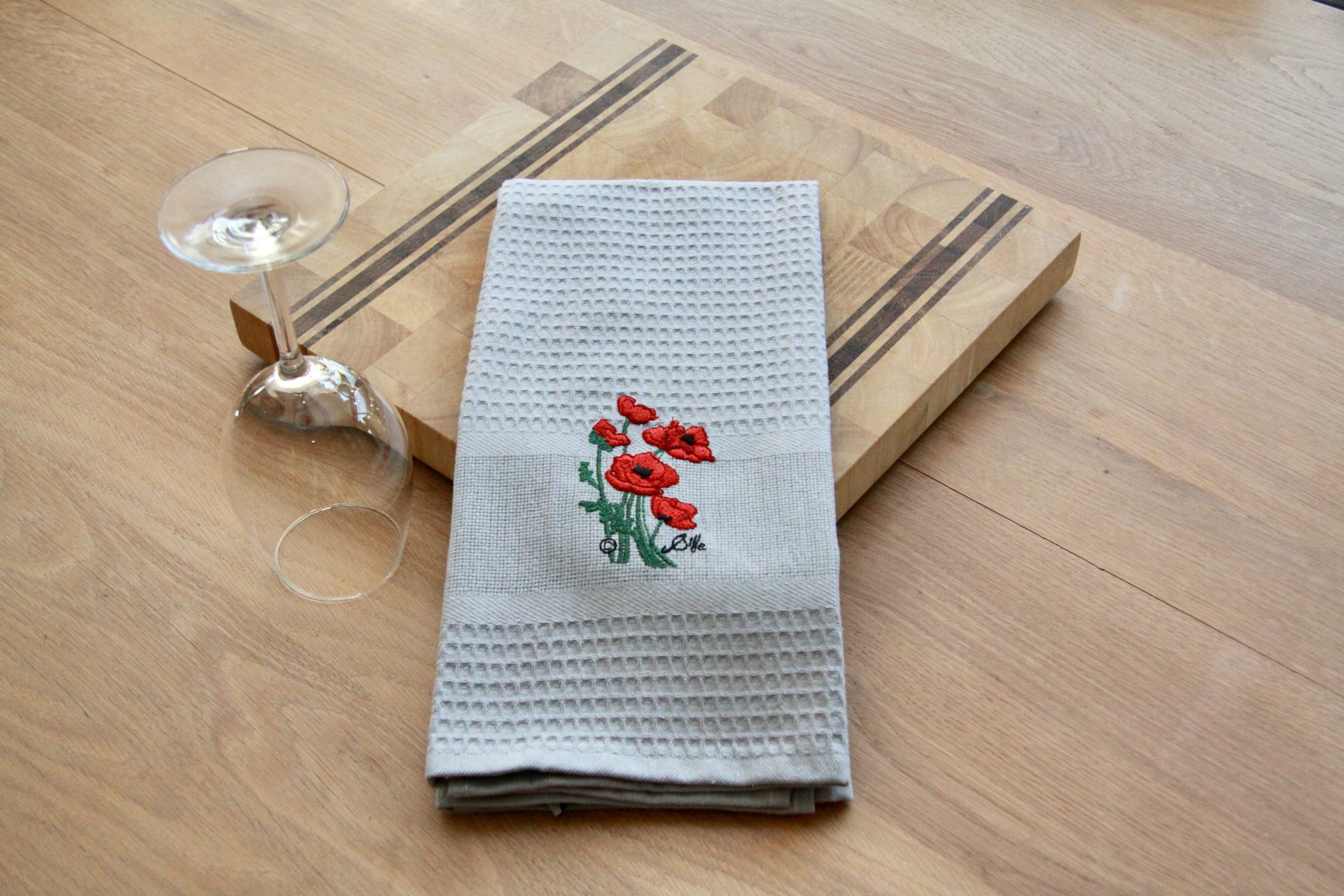 Torchon uni brodé de coquelicots, idéal pour la cuisine, avec un design élégant et artisanal.