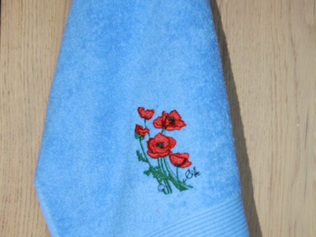 Serviette invité bleue avec broderie de coquelicots, fabriquée en France, reflet du style floral de Poppies Shop à Bayeux.