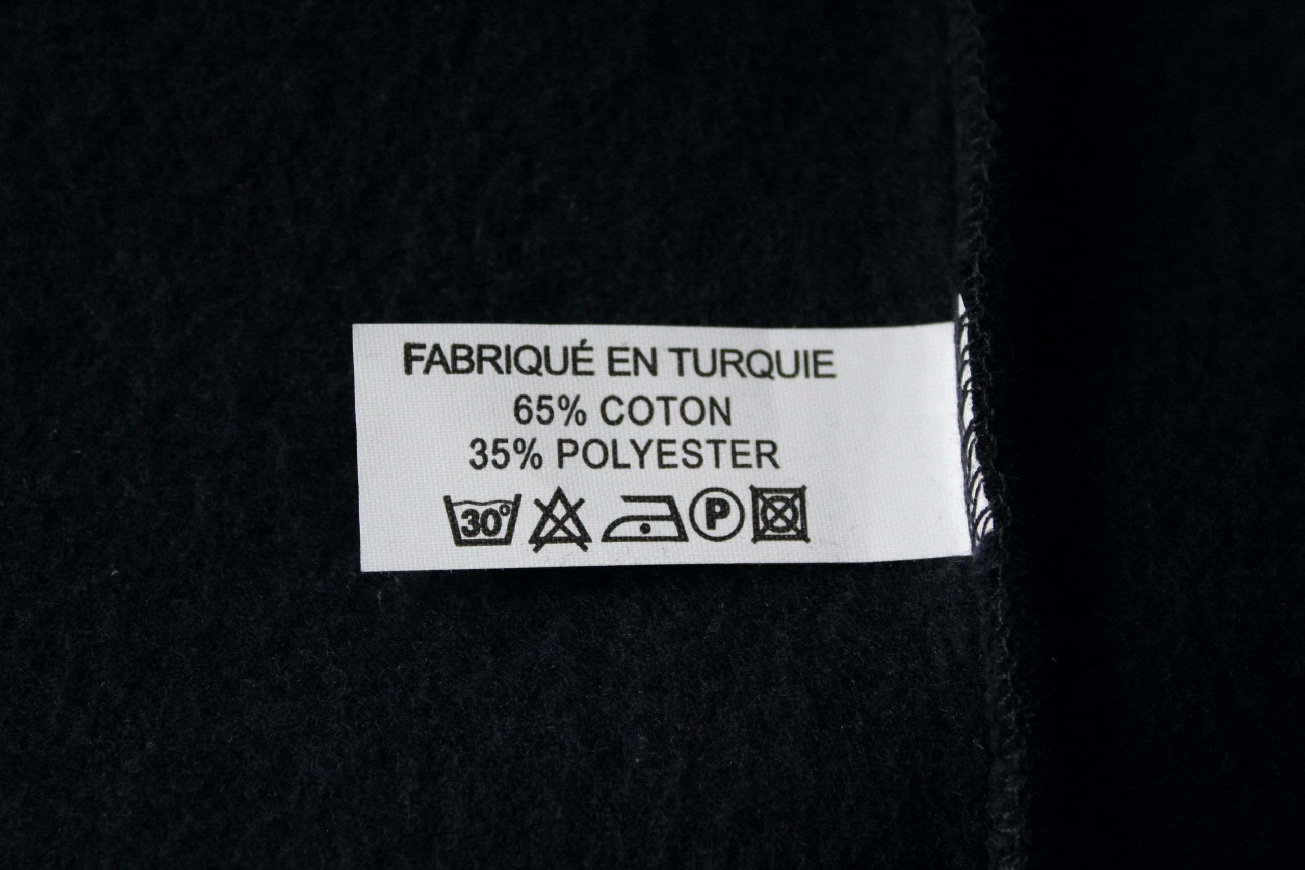 Étiquette d'entretien d'une veste zippée bleu marine, indiquant la composition et les instructions de lavage.